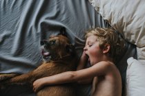 Menino dormindo na cama com seu cachorro — Fotografia de Stock