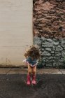 Девушка прыгает через лужи на дождливой улице — стоковое фото