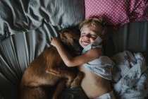 Junge umarmt seinen Hund im Bett — Stockfoto