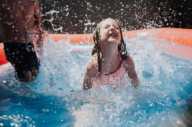 Girl splashing in a swimming pool — Stock Photo