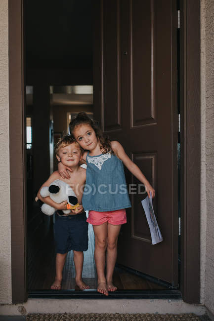Hermano pequeño y hermana de pie en la puerta - foto de stock
