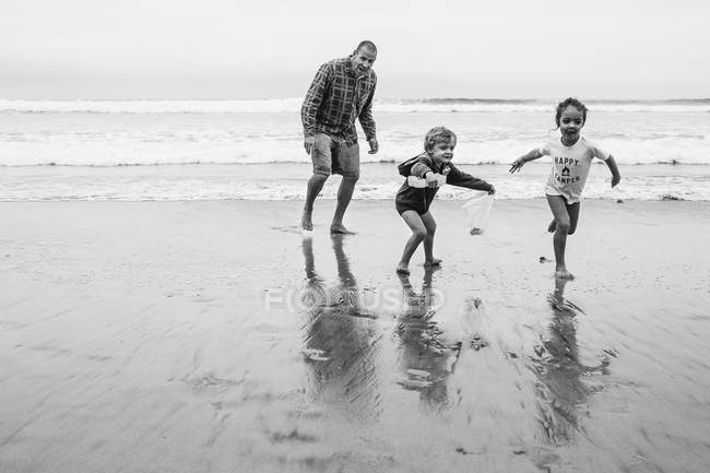 Pai com crianças na praia arenosa — Fotografia de Stock