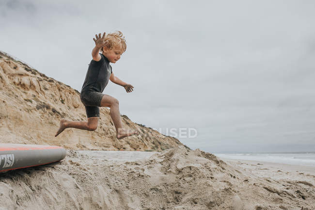 Garçon sautant et s'amusant sur la plage — Photo de stock