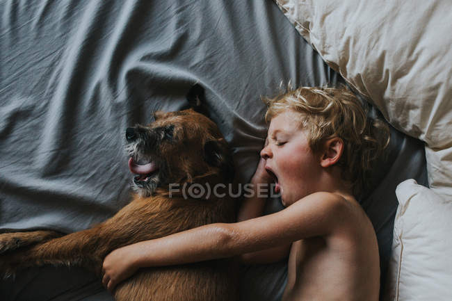 Garçon dormir dans le lit avec son chien — Photo de stock