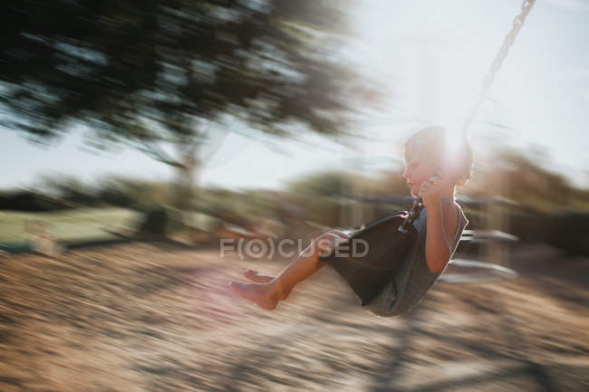 Garçon balançant sur une aire de jeux — Photo de stock