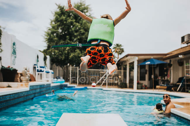 Niño en salto en la piscina - foto de stock