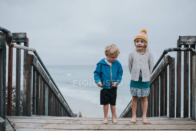 Brother and sister standing on wooden stairs — Stock Photo