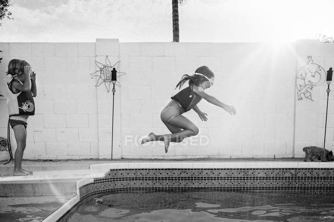 Girl jumping into a swimming pool — Stock Photo