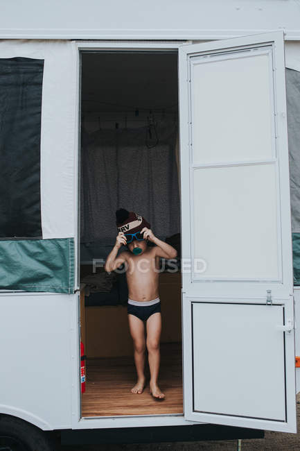 Niño de pie en la puerta del remolque de camping - foto de stock