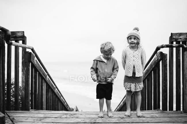 Children standing on wooden stairs — Stock Photo