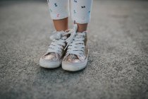 Female legs in colorful sparkling sneakers — Stock Photo