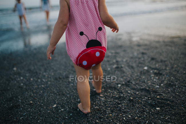 Девушка, идущая к морю на песке — стоковое фото