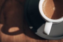 Xícara branca de café no pires escuro — Fotografia de Stock