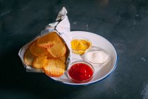 Potato chips with different sauces — Stock Photo