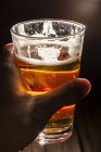 Glass of light beer in human hand. — Stock Photo