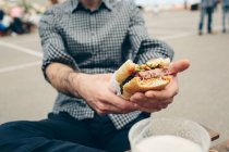 Homme tenant un sandwich à la viande — Photo de stock