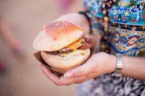 Hamburger in female hands — Stock Photo