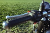 Volante de motocicleta e prado verde — Fotografia de Stock