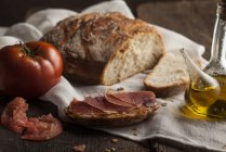 Bread and prosciutto on wooden table — Stock Photo