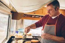 Mature homme cuisinier préparation hamburger — Photo de stock