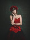 Чуттєва жінка в червоних квітах і сукні — стокове фото