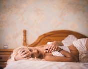 Jolie femme blonde allongée sur le lit — Photo de stock
