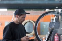 Hombre construyendo bicicleta en taller - foto de stock