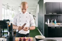 Chef in uniform cutting onion — Stock Photo