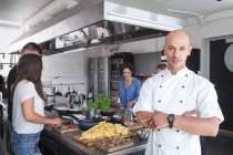 Koch mit Team kocht in der Küche — Stockfoto