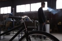 Constructed bicycle and smoking craftsman — Stock Photo