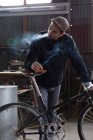 Ремесленник курит, держа в руках новый велосипед — стоковое фото