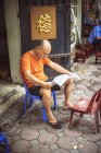 Vietnamese man reading newspaper in street — Stock Photo