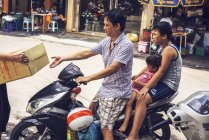 Homme conduite famille par moto — Photo de stock