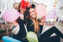 Meninas sorridentes em máscaras segurando balões — Fotografia de Stock
