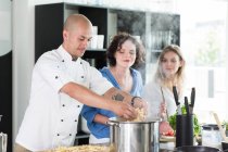 Chef enseñando cocina a mujeres - foto de stock