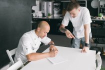 Chef writing on paper with student — Stock Photo
