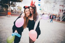 Улыбающиеся девушки в масках держат воздушные шары — стоковое фото