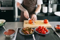 Cozinhe em avental de corte de tomates — Fotografia de Stock
