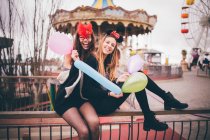 Chicas sonrientes con máscaras sosteniendo globos - foto de stock