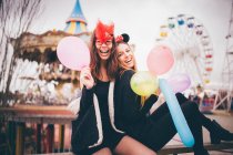 Meninas sorridentes em máscaras segurando balões — Fotografia de Stock