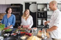 Fröhliche Frauen und Koch in der Küche — Stockfoto