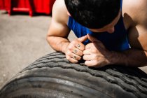 Bodybuilder with hands on tyre — Stock Photo