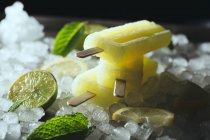 Lemon and lime popsicles on ice — Stock Photo