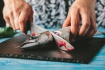 Woman cutting fresh mackerel — Stock Photo