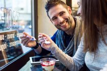Young couple eating iogurt in restaurant. — Stock Photo
