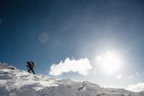 Escalador en la cima de la montaña nevada - foto de stock