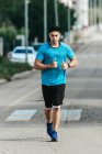 Sportsman running along city road — Stock Photo