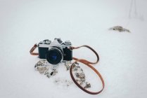 Vintage film camera on rock in snow — Stock Photo