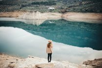 Vista posteriore della donna bionda in cappello al lago — Foto stock