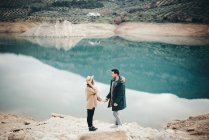 Вид збоку пари, що тримає руки проти озера — стокове фото